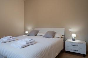 カスティオーネ・デッラ・プレゾラーナにあるBratto Relax Apartmentsのタオルが敷かれた白いベッドのある寝室