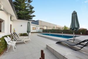 a patio with chairs and an umbrella and a pool at Casa São Domingos in Travanca