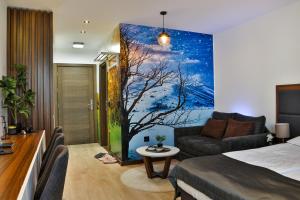 a bedroom with a bed and a painting of a tree at Zoned MASLAČAK lux - SPA & Wellness Kopaonik in Kopaonik