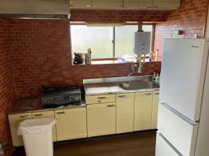 een keuken met een witte koelkast en een spoelbak bij 7Daysあさひや in Matsuzaki