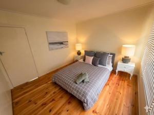 a bedroom with a bed with two lamps and a wooden floor at The Hamlyn Haven - Sleeps 5 - Central Location in Hamlyn Heights