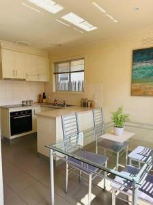 a kitchen with a glass table and chairs at The Hamlyn Haven - Sleeps 5 - Central Location in Hamlyn Heights