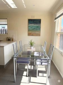 a dining room with a glass table and chairs at The Hamlyn Haven - Sleeps 5 - Central Location in Hamlyn Heights +3 photos
