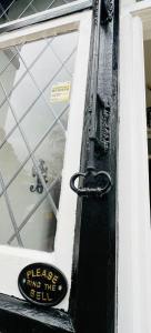 Eine schwarze Tür mit einem Schild drauf. in der Unterkunft The Norbury Hill Residence in West Norwood