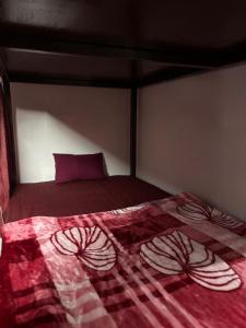 a bed with a red comforter in a bedroom at Shivanand Aashray - Near Sangam in Prayagraj