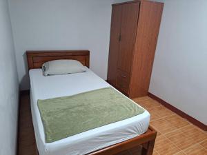 een kleine slaapkamer met een bed en een houten kast bij Casa Scarlet in Bangkok