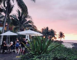 eine Gruppe von Personen, die an Tischen unter Sonnenschirmen am Strand sitzen in der Unterkunft Quiet Oceanside Casita Private Kitchen & Bath in Troncones