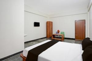 Hotel O Jodi Sri Muneshwara Swamy Temple في Jālahalli: غرفة نوم بها سرير وكرسي وتلفزيون