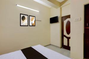 ein Schlafzimmer mit einem Bett und einem Fernseher an der Wand in der Unterkunft Hotel O Rela Hospital Chromepet Formerly Sri Ram Ganesh Residency in Chennai