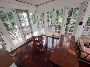 een kamer met een tafel, stoelen en ramen bij Casa Scarlet in Bangkok