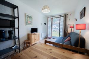 a living room with a blue couch and a window at Studio Cabine Ax Les 3 Domaines in Ax-Bonascre