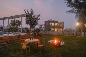 a table and chairs in a yard with a candle at Qila Hotel in Morādābād