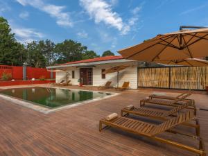 um pátio com cadeiras, um guarda-sol e uma piscina em The Hosteller Bam Coorg em Madikeri