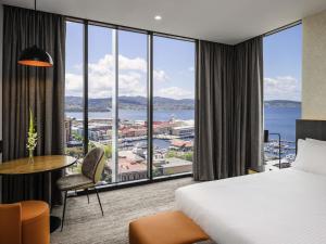 a hotel room with a bed and a large window at Mövenpick Hotel Hobart in Hobart