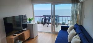 a living room with a blue couch and a tv and a balcony at A pasos de Reñaca, Gran Vista in Viña del Mar