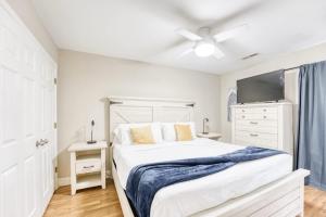 een witte slaapkamer met een bed en een plafondventilator bij Modern 4BR Retreat with Fire Pit in Bentonville