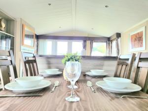 einen Esstisch mit einem Glas Wein darauf in der Unterkunft Lovely Caravan With Decking At Cherry Tree Park Norfolk Ref 70724C in Belton