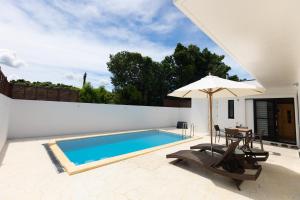 una piscina con tavolo e ombrellone di 2025年12月オープンのリベルテ瀬底サウナプールで整う1棟貸 a Sesoko