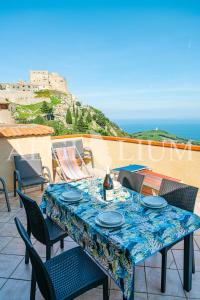 a table with a bottle of wine and chairs on a patio at Castello 4 in Isola del Giglio