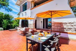eine Außenterrasse mit Tischen, Stühlen und Sonnenschirmen in der Unterkunft Estoril Royal Atlantic Villa with Ocean View in Estoril + 71 Fotos