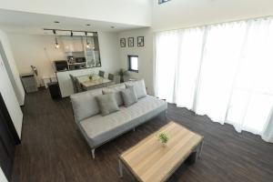 un soggiorno con un divano e un tavolo di 2025年12月オープンのリベルテ瀬底サウナプールで整う1棟貸 a Sesoko