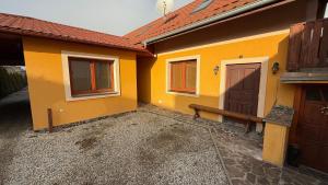 a yellow house with a bench and a door at 2 room apartment, Hriadky, Liptovsky Mikulas in Liptovský Mikuláš