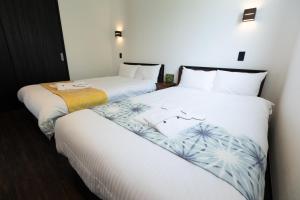 due letti uno accanto all'altro in una stanza di 2025年12月オープンのリベルテ瀬底サウナプールで整う1棟貸 a Sesoko Altre 62 foto