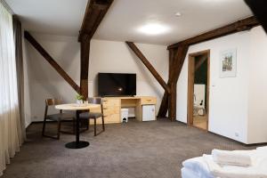a room with a desk and a tv and a table at Zámecká Konírna Hotel a Restaurace in Liberec