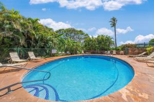 a large blue swimming pool with chairs and palm trees at Kaanapali Plantation 58 · KPL 58 Spacious 2BD Plantation Home Ne in Lahaina