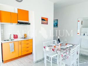 eine Küche mit orangefarbenen Schränken und einem Tisch mit weißen Stühlen in der Unterkunft Giuliana 4 in Campese + 4 Fotos