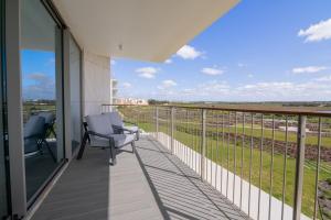 a balcony with two chairs and a view of a field at Bayline X in Armação de Pêra