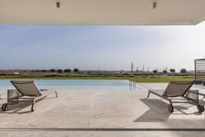 a pair of chairs sitting next to a swimming pool at Bayline X in Armação de Pêra