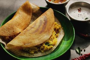 a green plate of food with two pita bread and dip at Super Hotel O Rajahmundry Central Railway Station Formerly Sanjeevi Residency in Godāvari