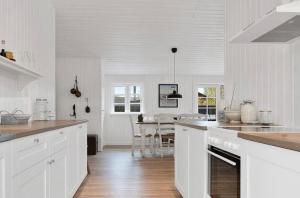 a kitchen with white cabinets and a dining room at Beach House Near Sejerø Bay in Hønsinge