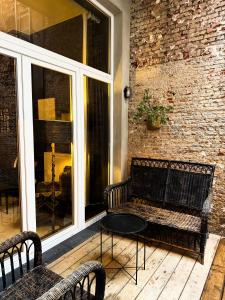 een bank op een veranda met een tafel en een bakstenen muur bij Sān home’s in Antwerpen