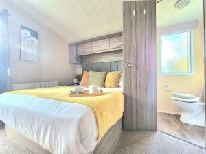 ein Schlafzimmer mit einem großen Bett und einem WC in der Unterkunft Lovely Caravan With Decking At Cherry Tree Park Norfolk Ref 70724C in Belton