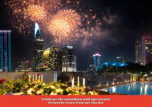 Un espectáculo de fuegos artificiales sobre el horizonte de una ciudad con una piscina. en Happy Life Grand Hotel & Rooftop Skybar, en Ho Chi Minh