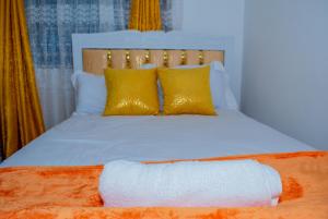 a bed with yellow pillows and a white blanket at Delsy Stays in Ruaka