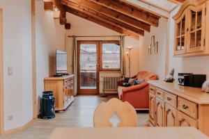 a kitchen and living room with a couch and a tv at Gästehaus Wechs - inklusive Hindelang PLUS in Bad Hindelang