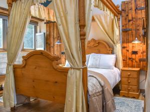 ein Schlafzimmer mit einem Himmelbett in einem Zimmer mit Holzwänden in der Unterkunft Little Penquite in Landrake