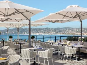 a restaurant with tables and chairs and umbrellas at The 1932 Hotel & Spa Cap d'Antibes - MGallery Collection in Juan-les-Pins