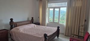 una camera da letto con un letto e una grande finestra di Gardenia a Kandy