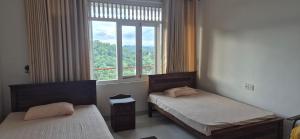 due letti in una stanza con una grande finestra di Gardenia a Kandy