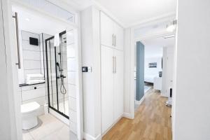 une salle de bain blanche avec toilettes et miroir dans l'établissement Camden Serviced Apartments by Globe Apartments, à Londres 58 autres photos