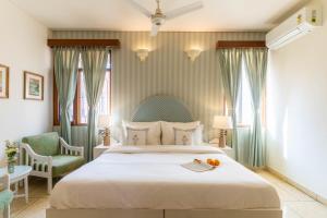 een slaapkamer met een groot wit bed en een stoel bij Jobner Haus Jaipur in Jaipur