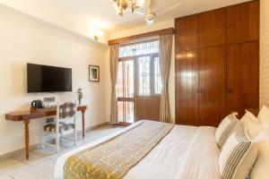 a bedroom with a bed and a desk and a television at Jobner Haus Jaipur in Jaipur