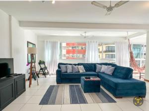 a living room with a blue couch and a tv at Aproveitando o Sol e o Mar de Torres in Torres