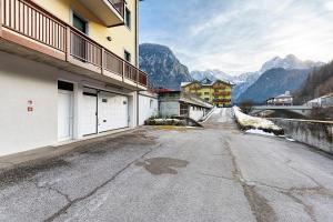 eine leere Straße vor einem Gebäude mit Bergen in der Unterkunft Residence Le Ante - Cadore in Santo Stefano di Cadore