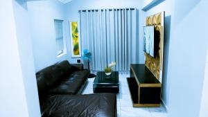 a living room with a black leather couch and a television at DC Guest House in Avondale