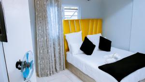 a bedroom with a bed with white sheets and black pillows at DC Guest House in Avondale